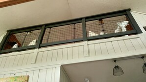 Tilava ullakkoasunto, jossa on korkea katto, puupalkit, keittotila ja näkymä ulos.