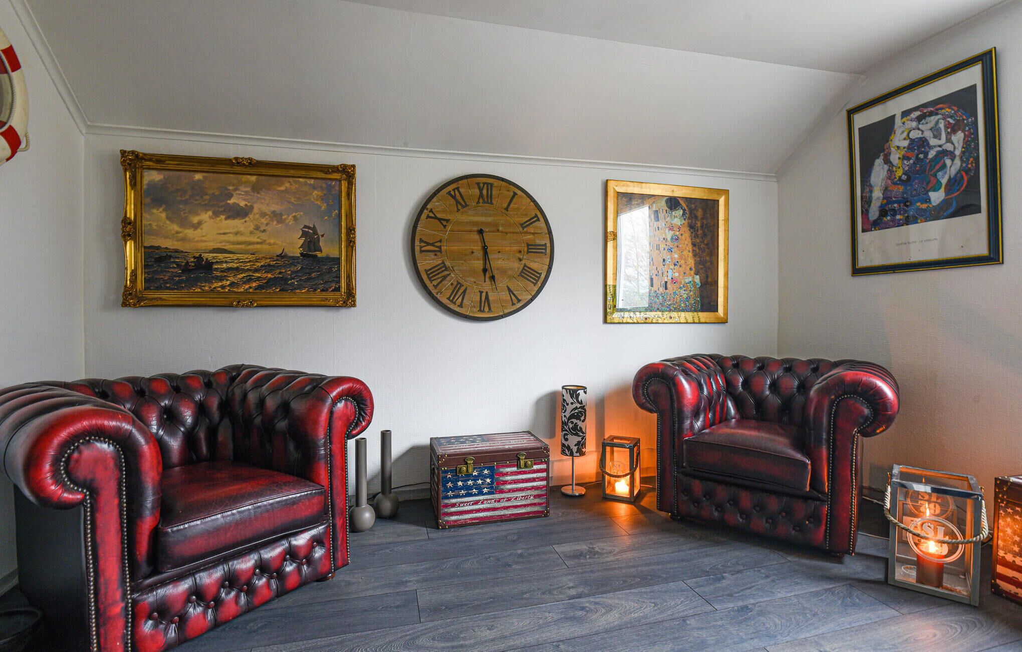 Une pièce comprenant deux fauteuils en cuir, une grande horloge en bois et des œuvres d’art encadrées accrochées aux murs.