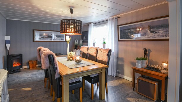 A cozy dining area with a wooden table, chairs, and a central light fixture.