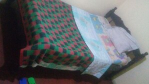 A bed with a checkered blanket and a patterned pillow. - Kiuu Guest House (Ruiru)