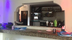 A bar area with shelves of bottles, a counter with various items, and a door leading to another room. - Milimani Hotel (Kakamega)