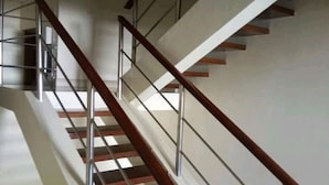 A modern staircase with wooden steps and metal railings, leading to an upper floor. - Milimani Hotel (Kakamega)