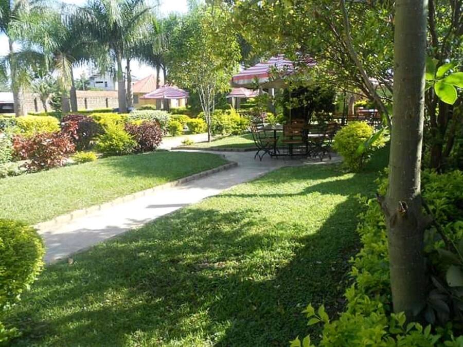 A well-maintained garden with a paved walkway leading to a seating area with tables and chairs.