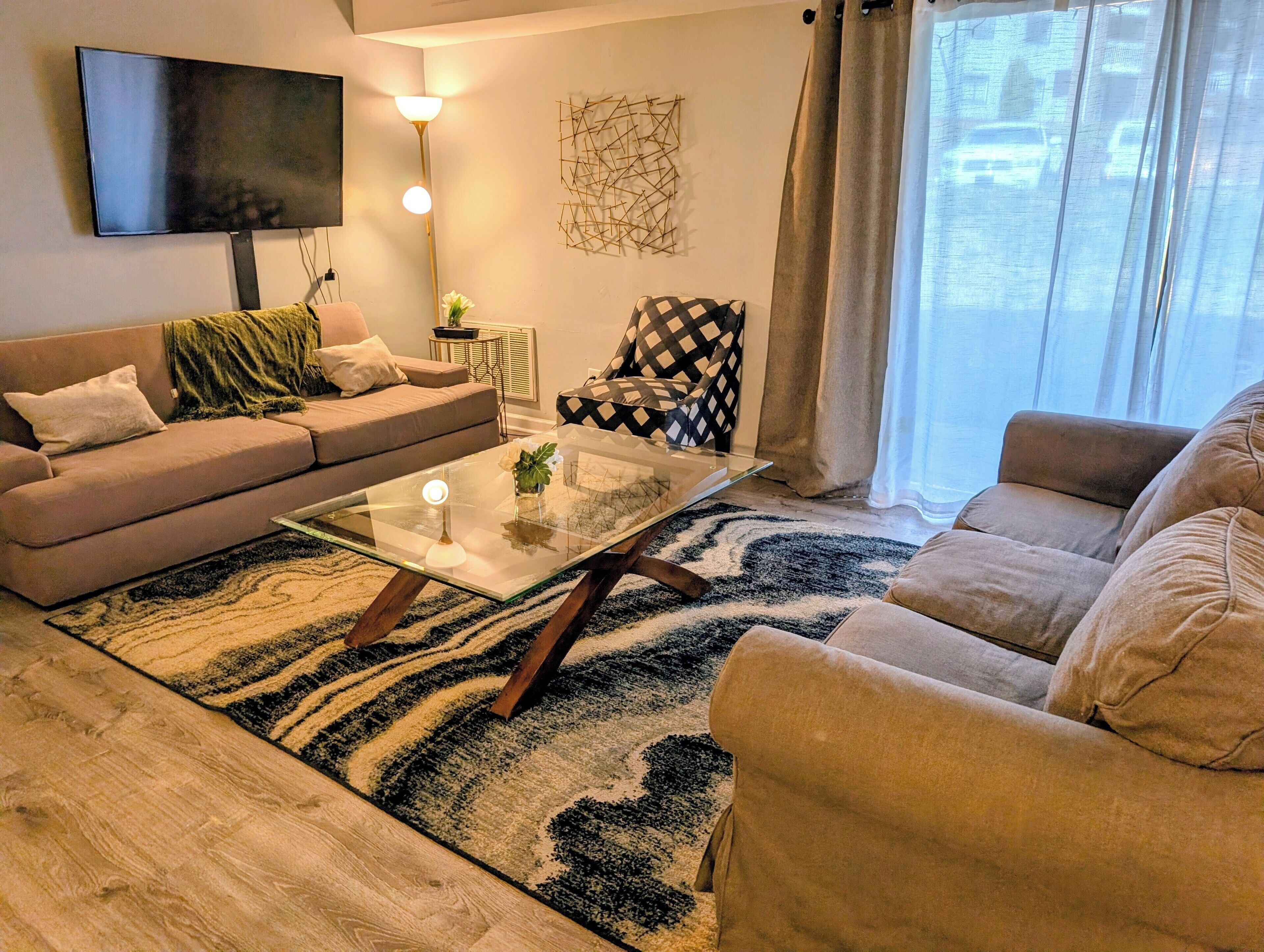 En stue med et fladskærms-tv, et glasbord og to sofaer.