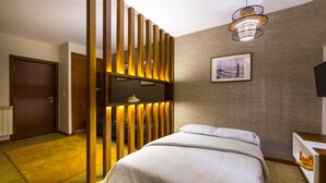 A bedroom with a bed, a wooden partition, a framed picture on the wall, and a ceiling light fixture. - Flat Casino Beach Figueira da Foz - Moderno & Ótima Localização! (Figueira da Foz)