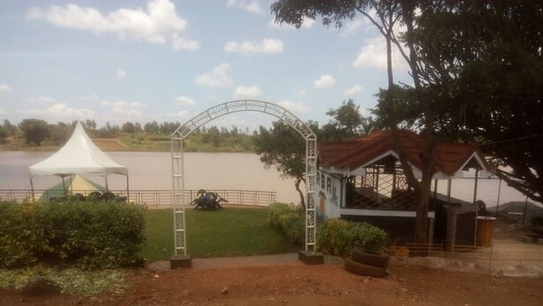 A dirt path leading to a white tent and a gazebo by a lake. - Rock Beach Resort (Ruiru)