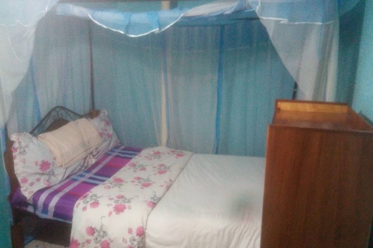Quarto com cama, mesa de cabeceira e dossel.