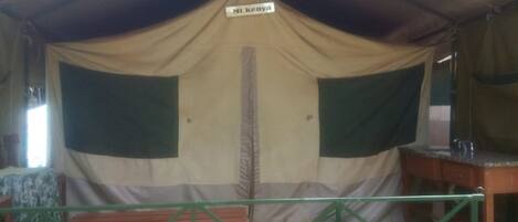 A tent with a sign reading "Mi Kenaya" and a green-framed table in the foreground.