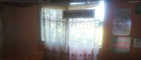 A reception area with a sign indicating the agent number and a 'Reception' sign above a window with a curtain.