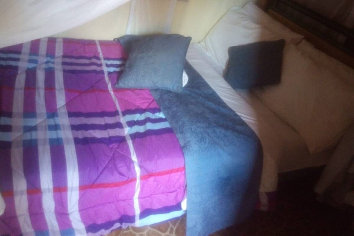 Uma cama com um cobertor listrado e duas almofadas.