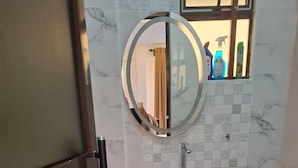 A bathroom with a wooden vanity, a round mirror, and a tiled floor. - Sailors Hotel (Mlolongo)