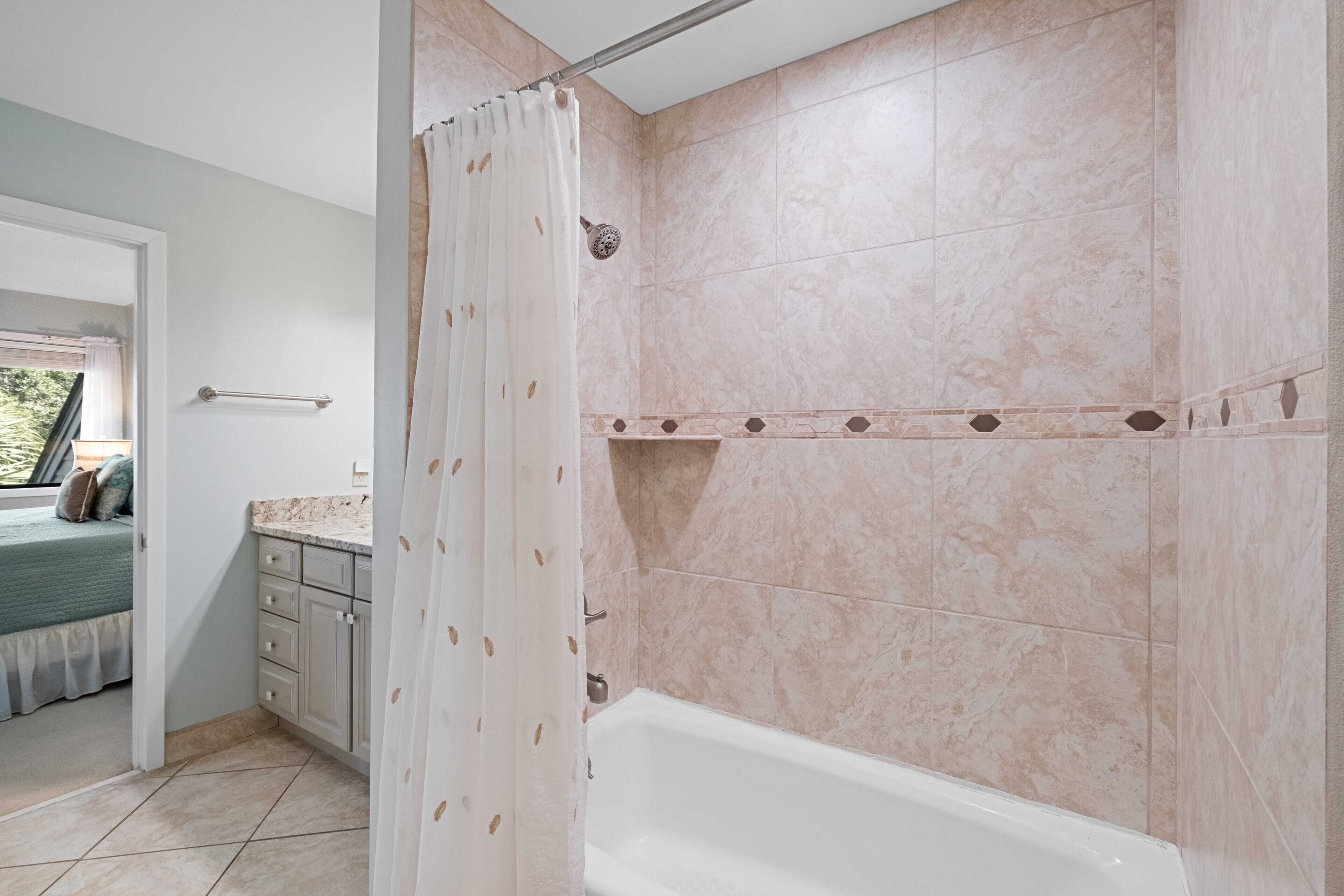 Un baño con bañera, ducha y ventana con vistas a zonas verdes.