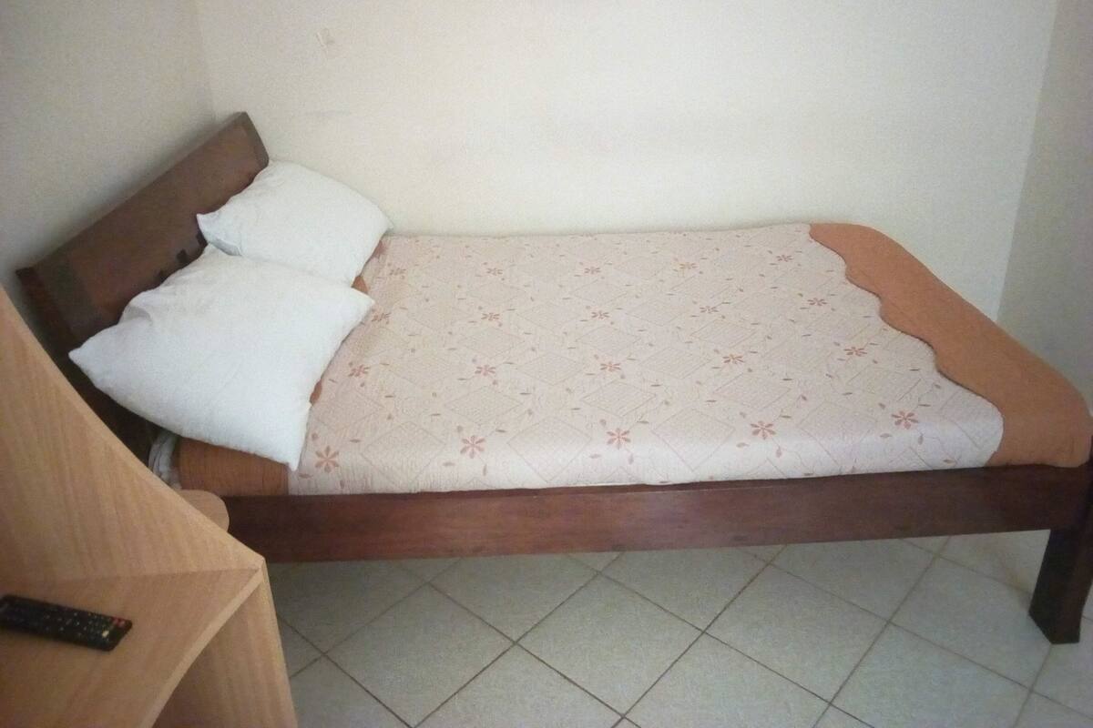 A single bed with a wooden frame and a patterned bedspread.