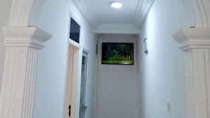 Un couloir aux murs blancs, un plafond doté d’un éclairage encastré et une porte au fond.