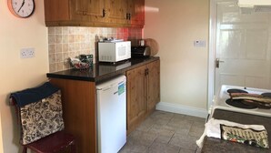 Une cuisine avec des meubles de rangement en bois, un four à micro-ondes, un grille-pain et un réfrigérateur.