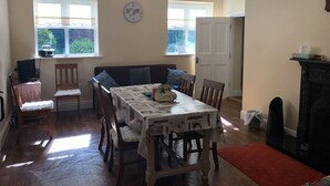 Une salle à manger avec une table en bois, des chaises et une horloge au mur.