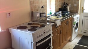 Une cuisine compacte équipée d’une cuisinière, d’un four et d’un lave-linge.