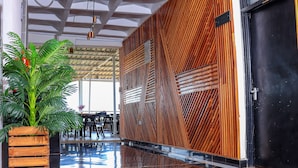 Un hall espacioso con diseño moderno, que presenta un panel de pared de madera, una puerta negra grande y una planta en maceta.