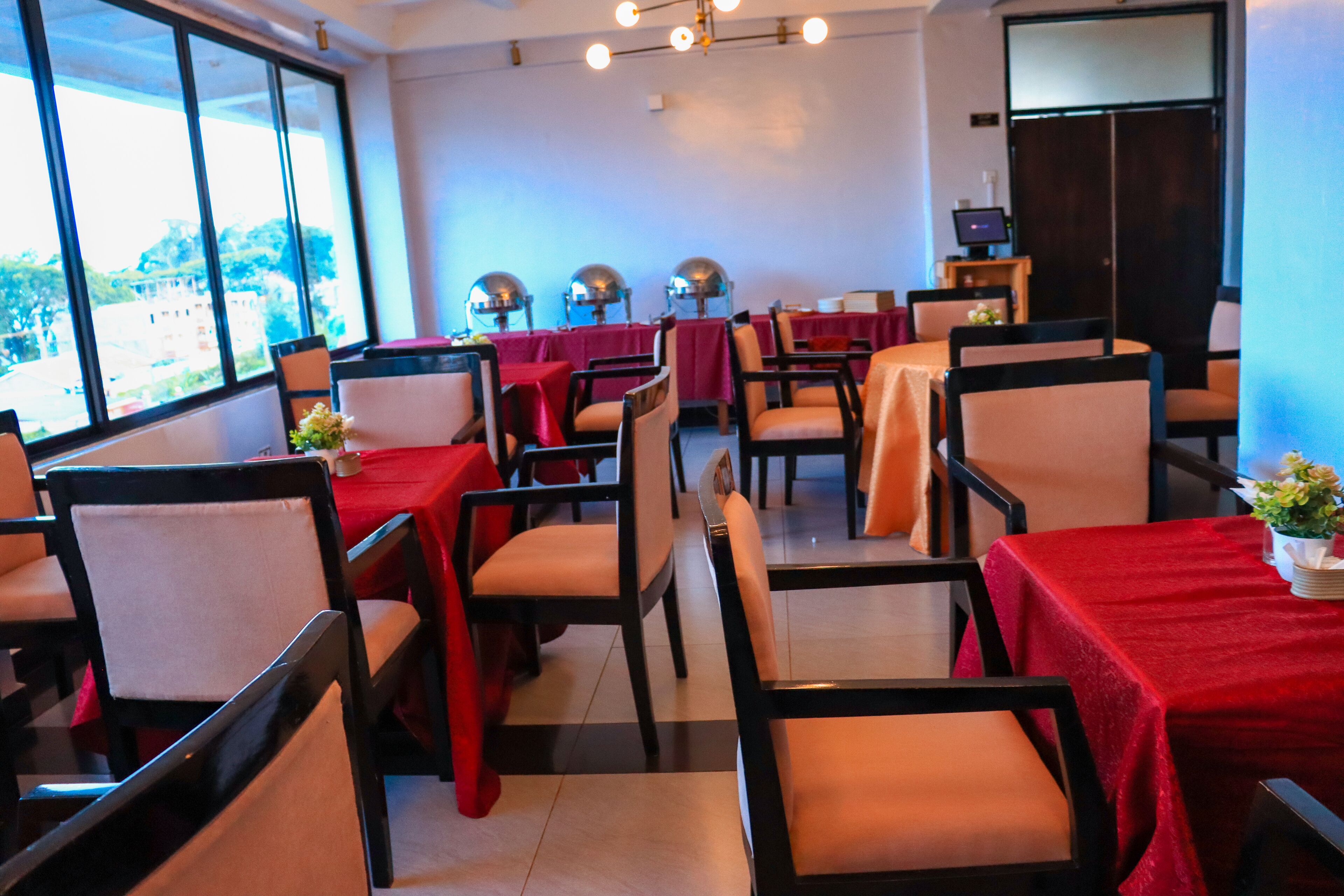 Een restaurant met tafels bedekt met rode tafelkleden, gerangschikt in rijen met stoelen.