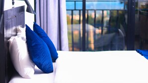 Habitación de hotel con cama, almohadas, mesita de noche y ventana con vistas al exterior.