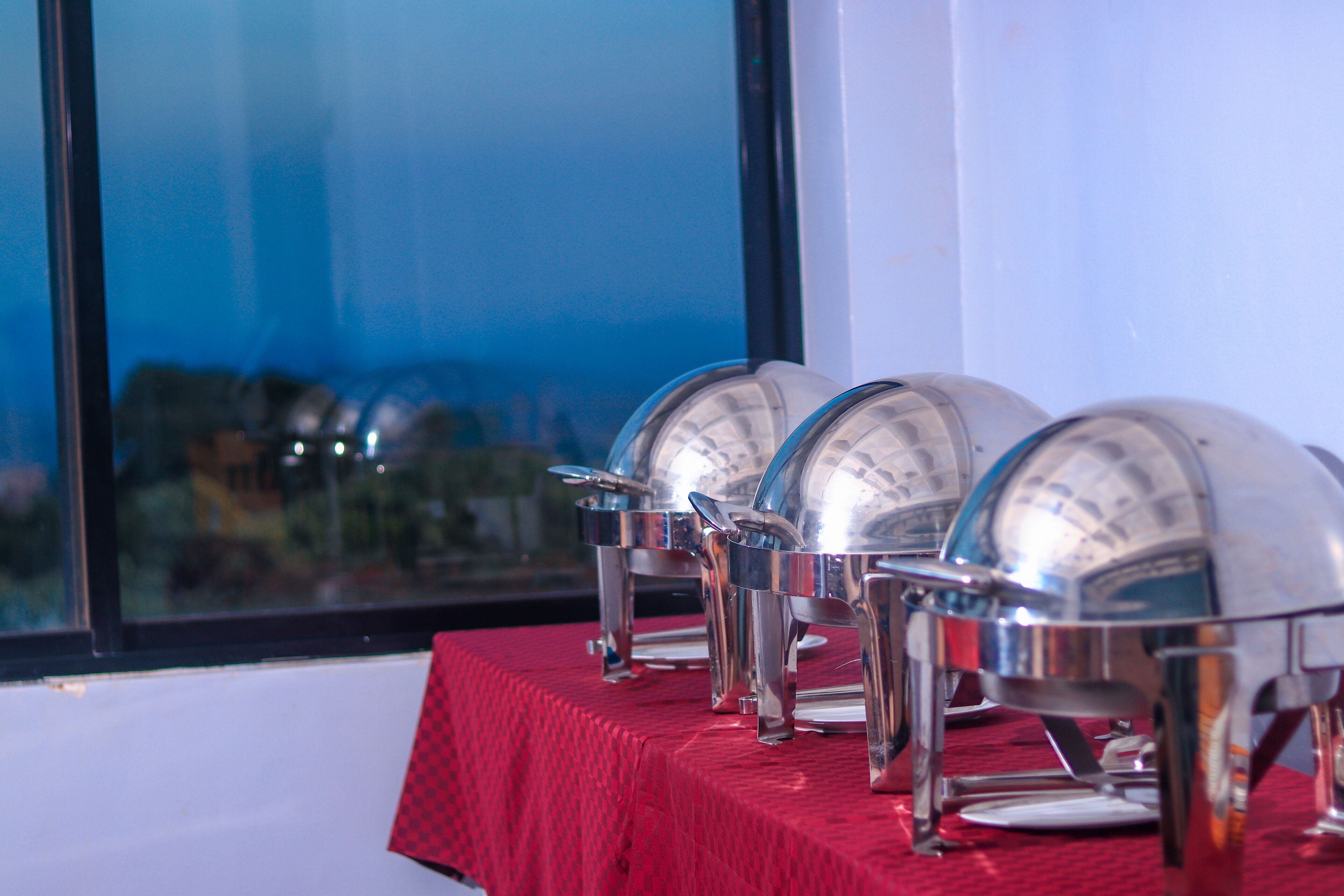 A table with three large, metallic, dome-shaped objects, possibly for serving food, set against a red tablecloth.
