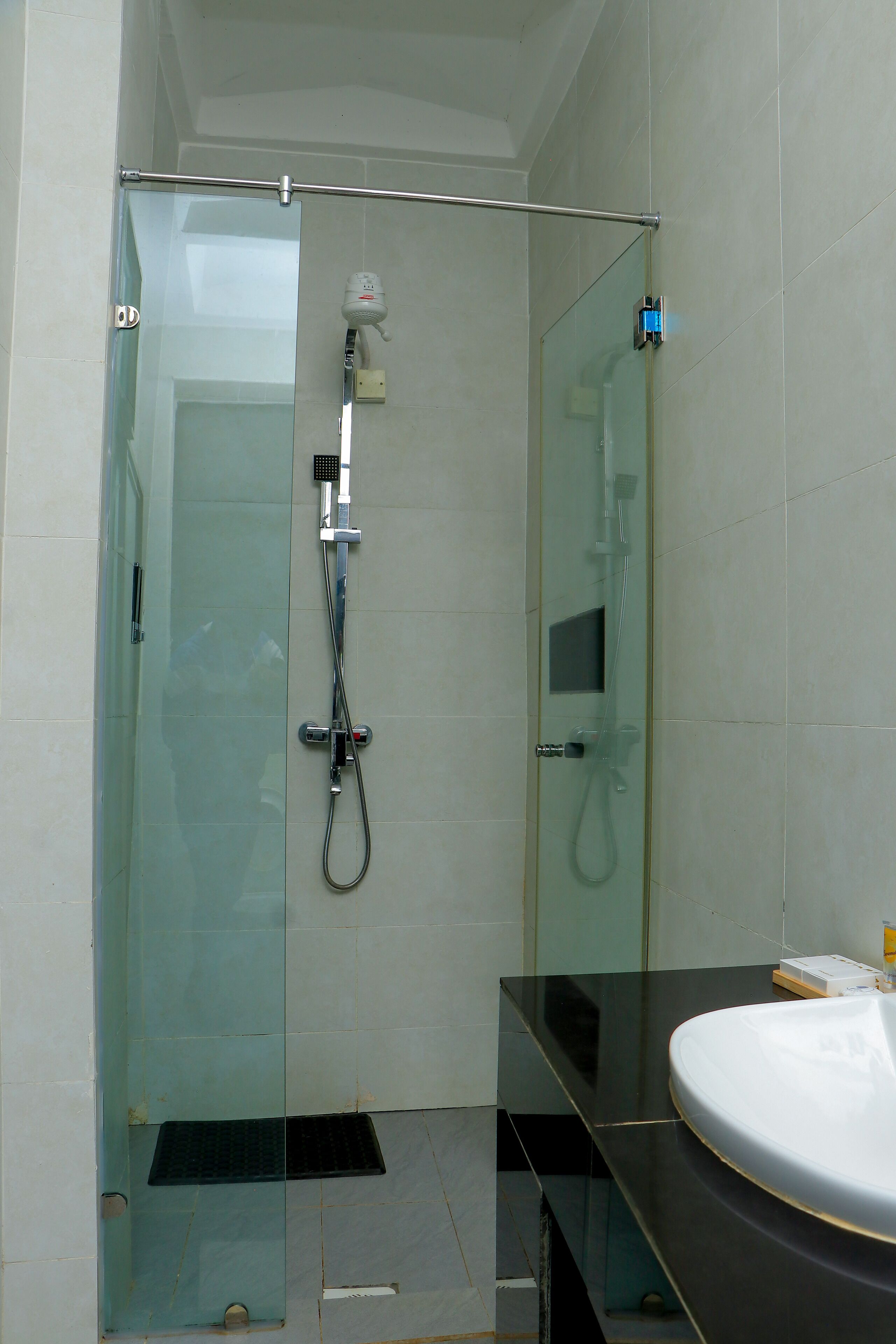Un baño moderno con ducha de vidrio, encimera negra y lavamanos blanco.