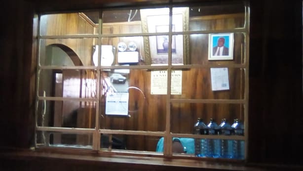 Ventana de madera con múltiples divisiones, un interior visible con una barra y botellas, y un cuadro enmarcado a la derecha.