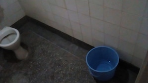 Un baño con un inodoro y un cubo azul.