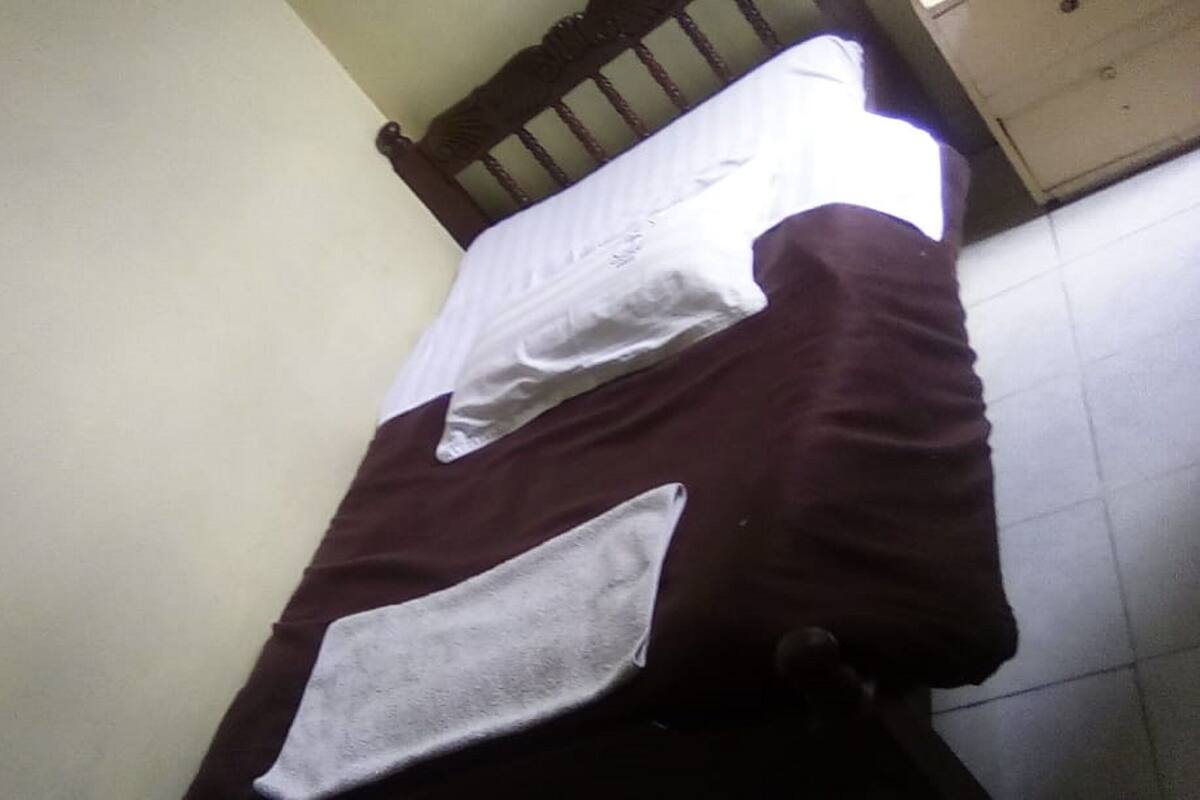 A room with a bed, a white pillow, and a brown blanket.