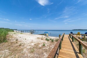 Relax on the beach with comfortable seating and umbrellas along the boardwalk, overlooking the calm sea.