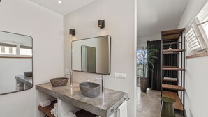 A modern bathroom with a large mirror, two sinks, and a wooden shelf. - PM78 Boutique Apartments (Willemstad)