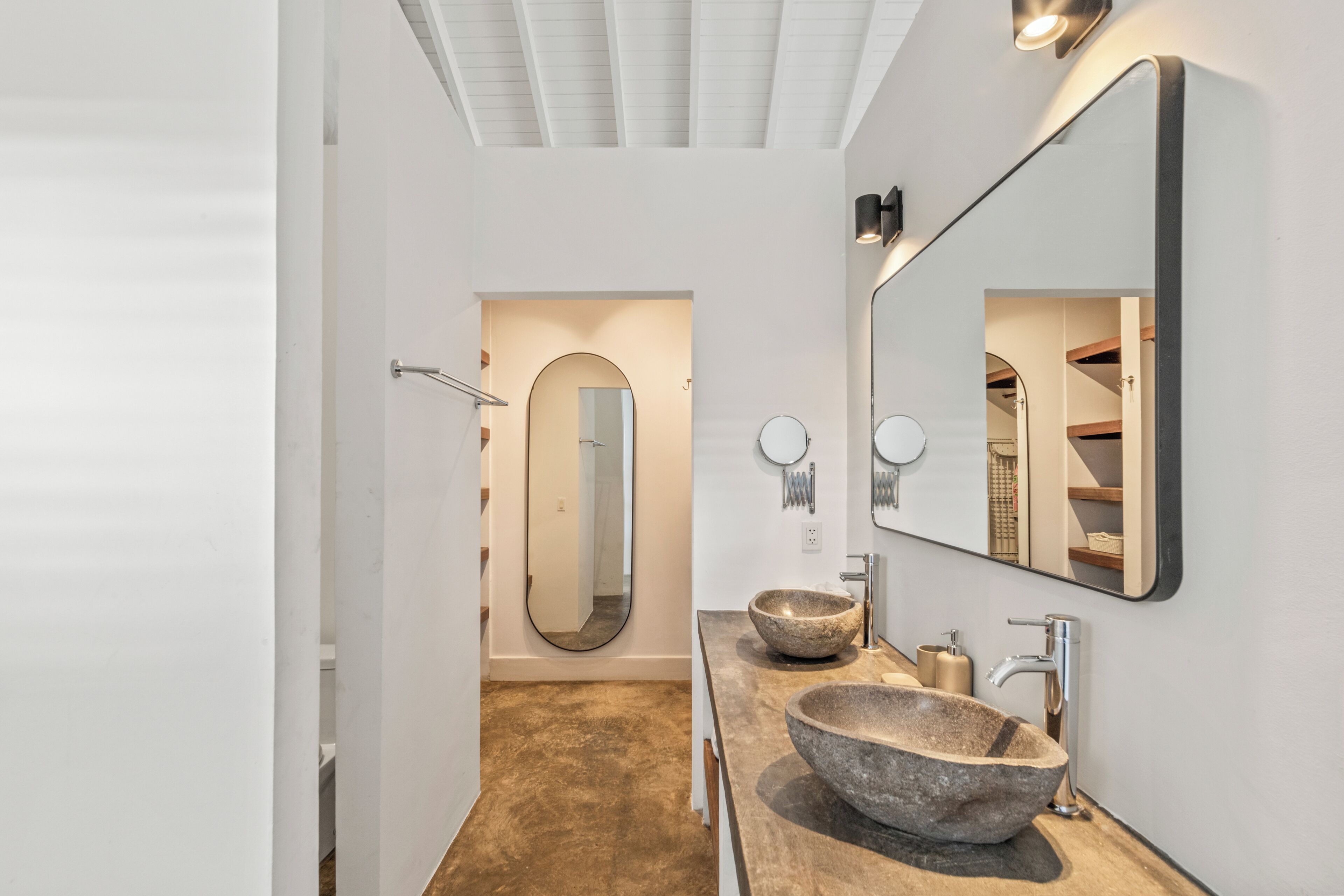 Un bagno moderno con uno specchio grande, due lavabi in pietra e una cabina doccia.