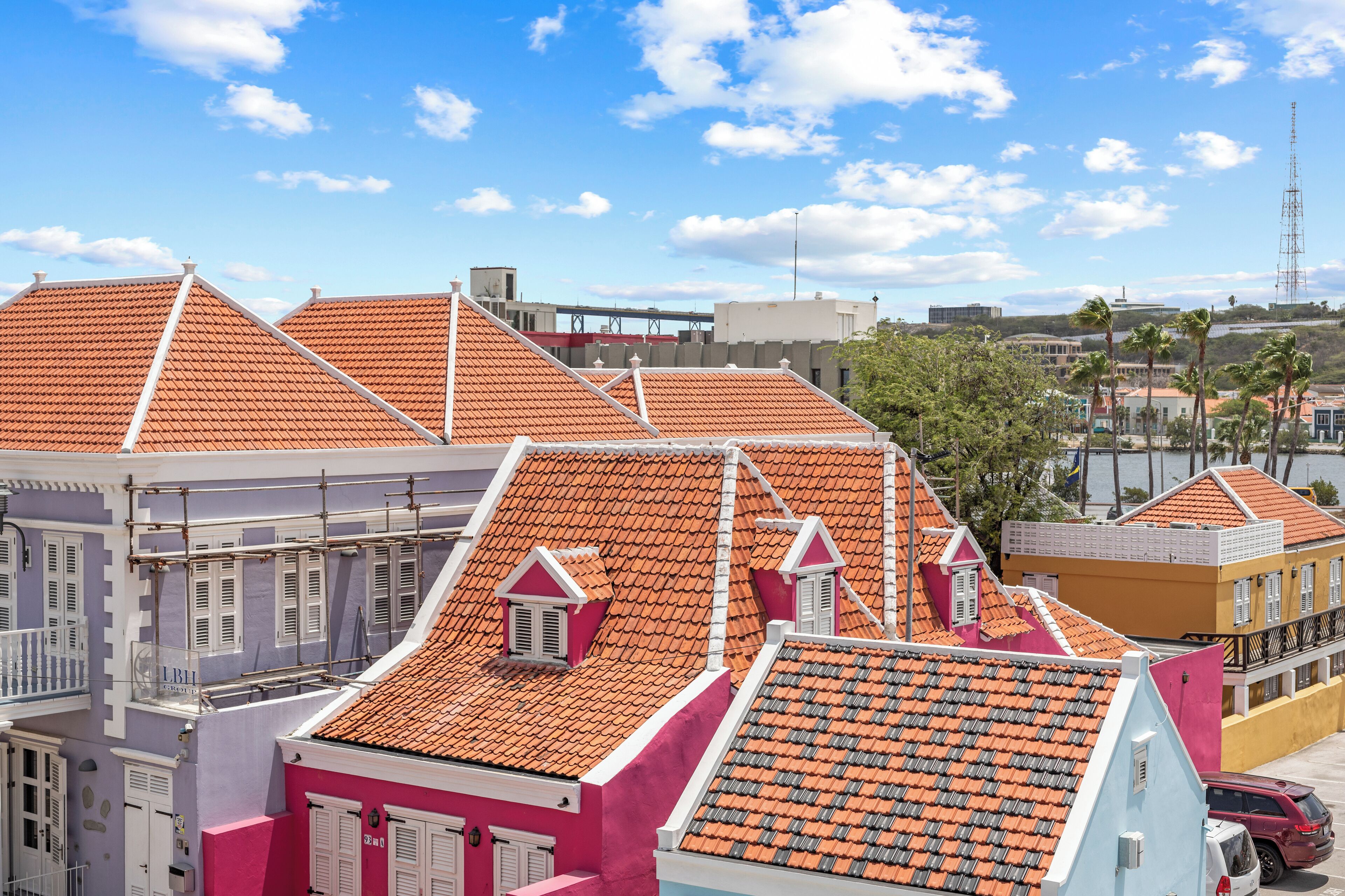 A row of colorful buildings with orange tiled roofs and balconies.