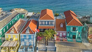 A coastal area with colorful buildings, a beach, and a view of the sea. - PM78 Boutique Apartments (Willemstad)