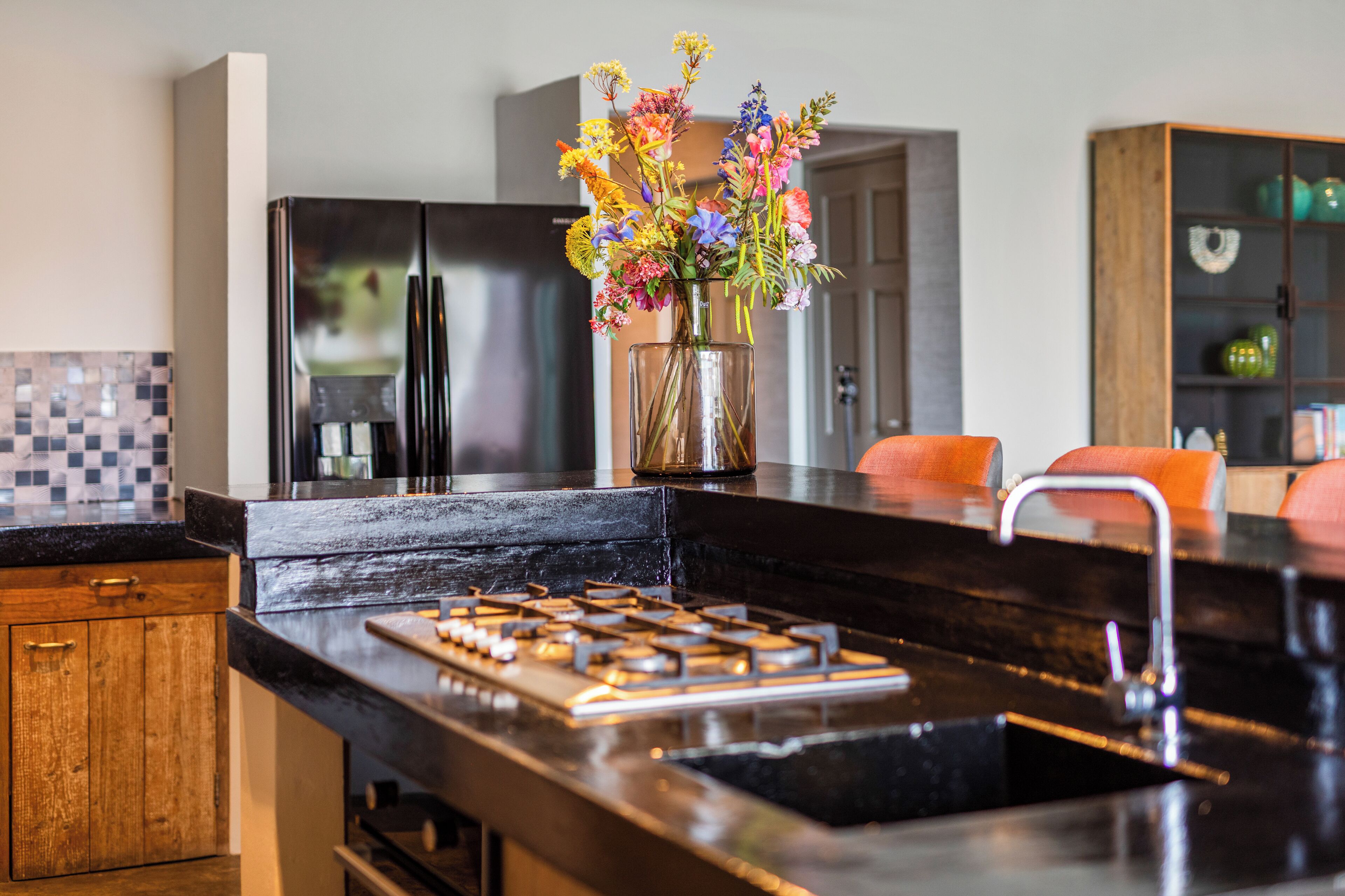 Una cocina moderna con un refrigerador de acero inoxidable, una estufa a gas y un florero con flores en la encimera.