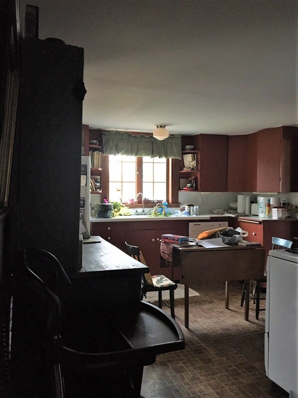 A kitchen with a dining table, chairs, and a refrigerator.