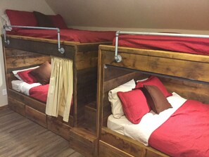 Twee stapelbedden met houten frames en rode beddengoed.
