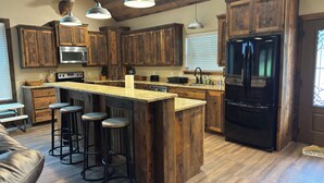 Una cocina con armarios de madera, un refrigerador negro y una barra con taburetes.