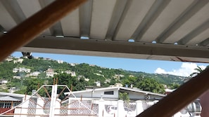 Vista de una zona residencial con casas en una ladera, una valla metálica blanca y cielo despejado.