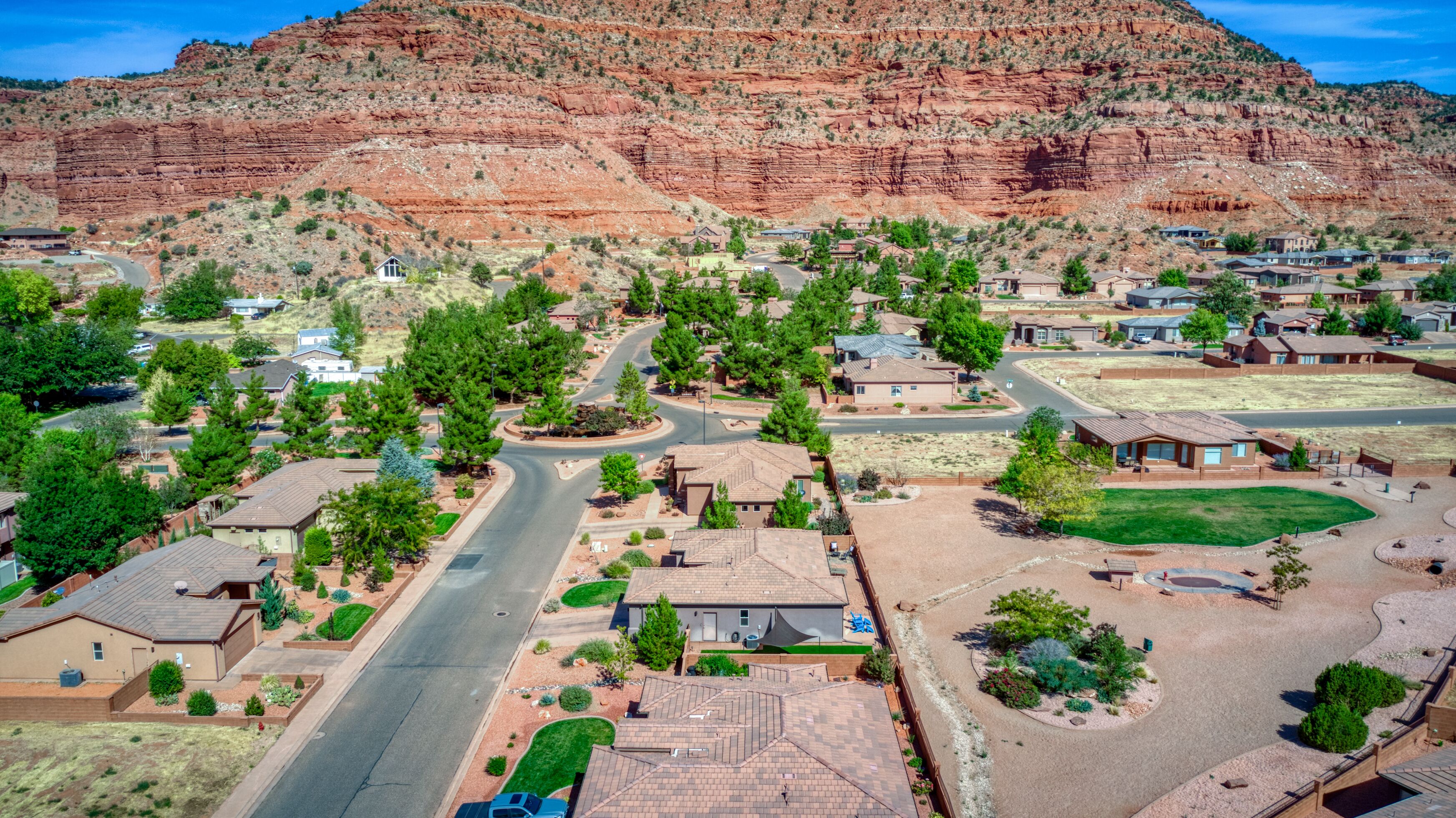 Un barrio residencial con casas, caminos y una montaña al fondo.