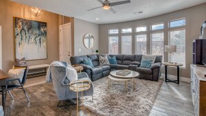 A spacious living room with a sectional sofa, a round coffee table, and a large painting on the wall.