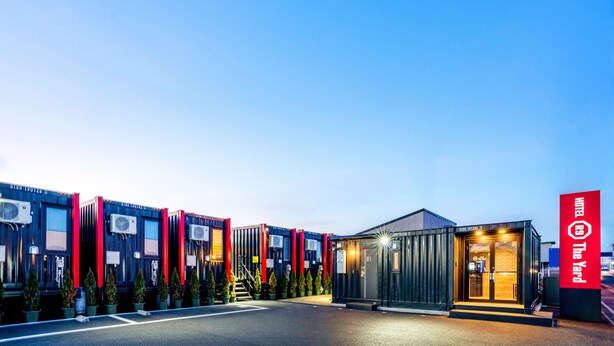 A hotel with a modern design, featuring a central building with a glass entrance and a red sign. - Hotel R9 The Yard Oyamakizawa (Oyama)