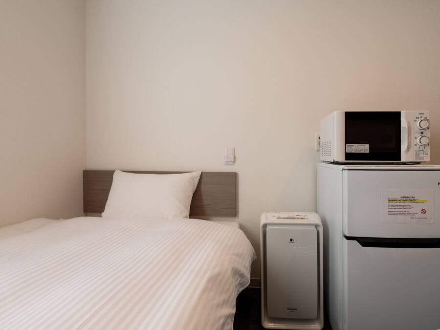 Una habitación de hotel con cama, microondas y refrigerador.
