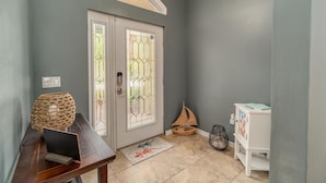 A hallway with a double door, a wicker lamp, a small table with a book, a decorative basket, and a white cabinet. - Located 6 miles from 4 major beaches & walking distance to Shamrock Nature Park (Venice)