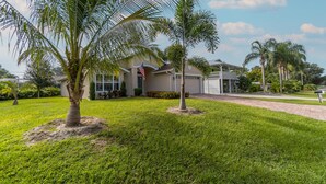 A residential house with a well-maintained lawn, palm trees, and a clear sky. - Located 6 miles from 4 major beaches & walking distance to Shamrock Nature Park (Venice)