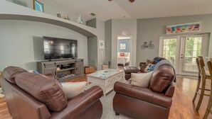 A living room with a flat-screen TV, leather sofas, a coffee table, and a ceiling fan. - Located 6 miles from 4 major beaches & walking distance to Shamrock Nature Park (Venice)