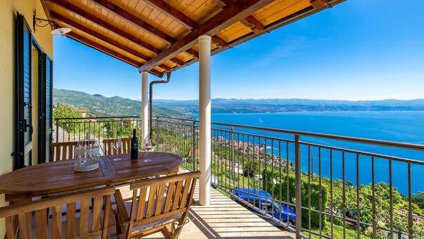 Um deck de madeira com mesa e cadeiras, de frente para a vista costeira.