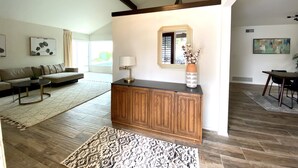 A spacious living room with a wooden cabinet, a sofa, and a large window. - The Litchfield Park Place w/ Heated Pool near Wigwam Golf Resort & State Farm (Litchfield Park)