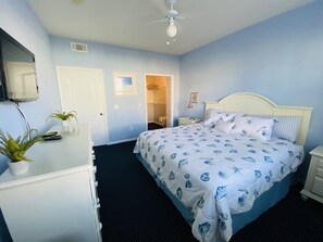 Un dormitorio con cama, cómoda y ventilador de techo.