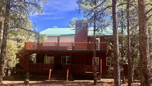 A two-story cabin with a balcony, surrounded by trees. - Majestic Mountain Getaway - Jenson's TreeHouse, a Spacious Cabin Retreat. (Show Low)